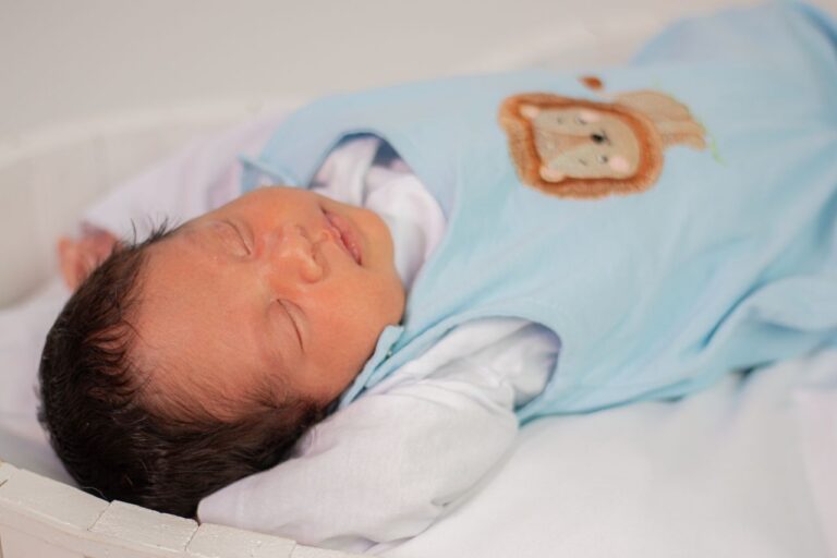 A serene newborn baby sleeps peacefully in a light blue outfit with animal designs.